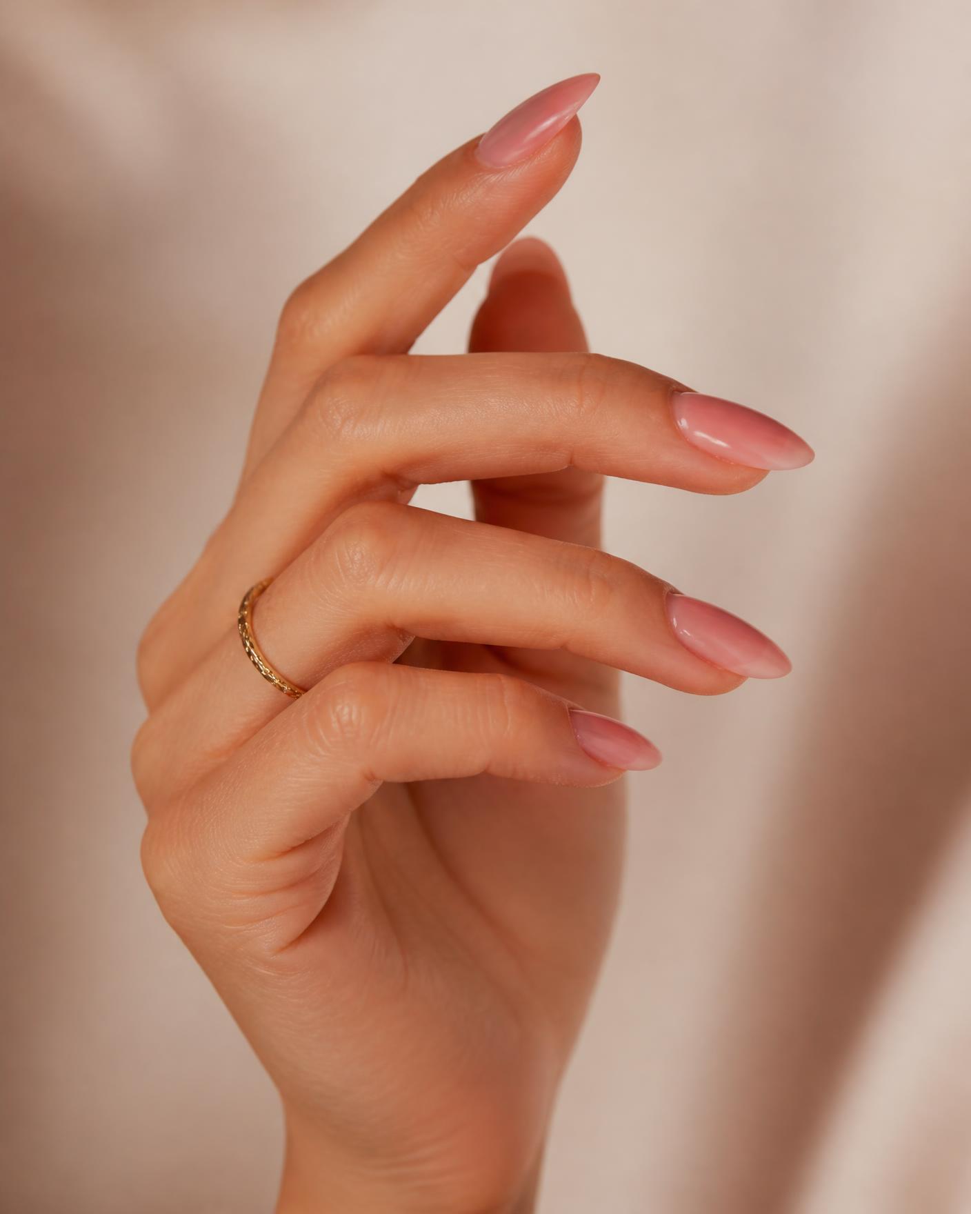 Hand with glossy blush almond press-on nails floating in a starry sky